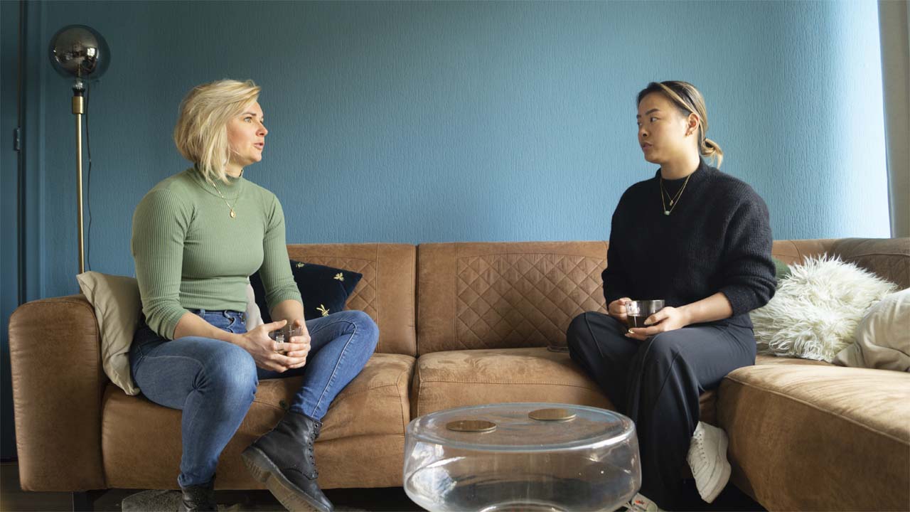 Leefstijl coach die een gesprek voert met een vrouwelijk client zittend op een bruine bank.