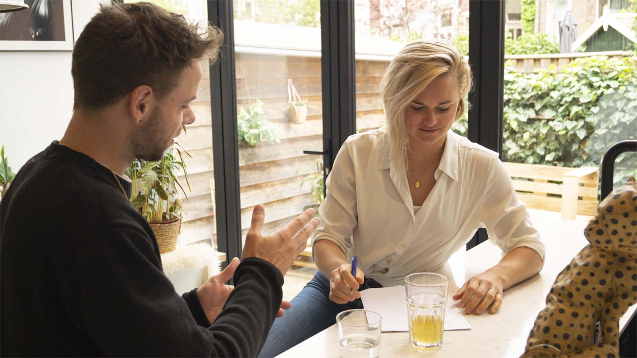 Leefstijl coach die een gesprek voert met een mannelijke client aan een bartafel onder het genot van een gemberthee.