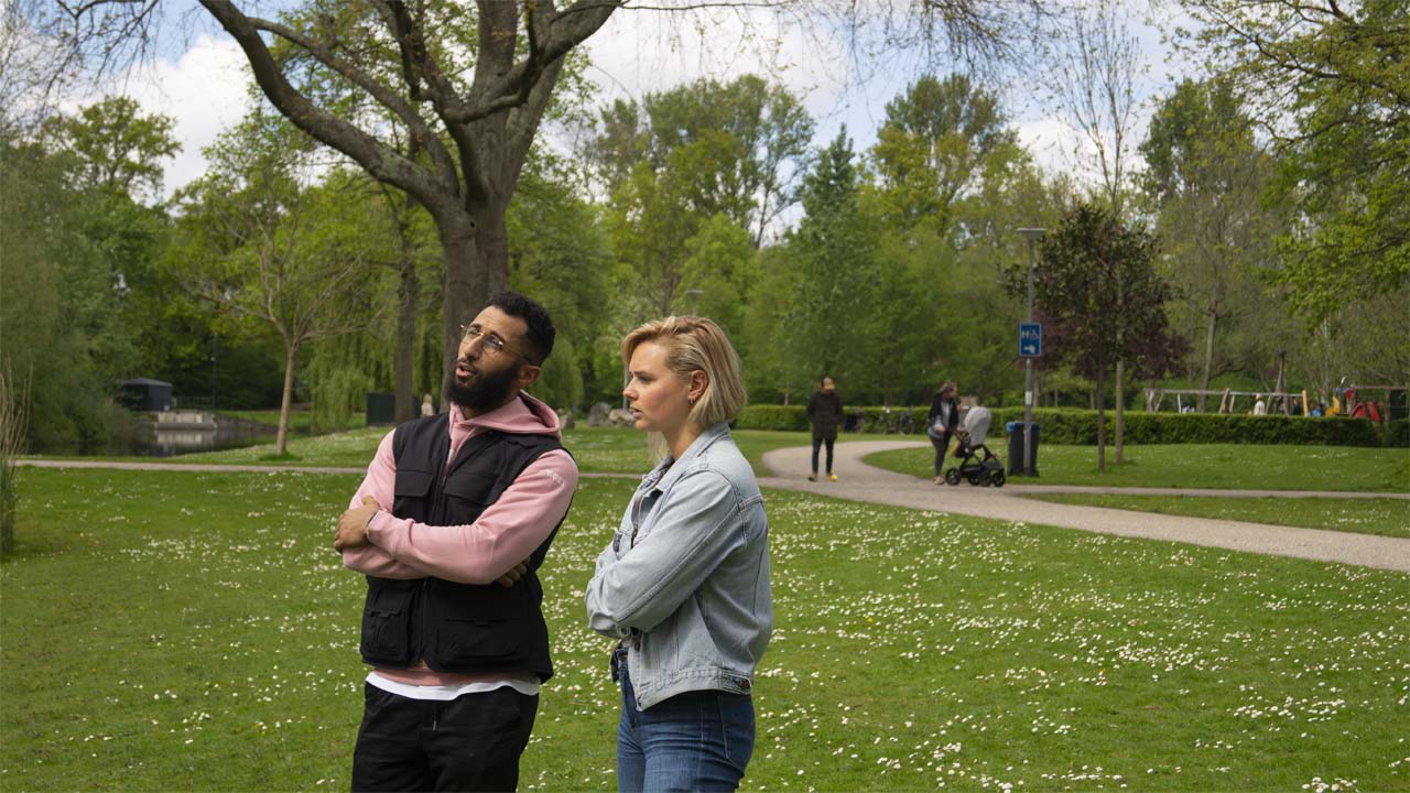 Linde die een gesprek voert met een client beide staand met het park op de achtergrond.